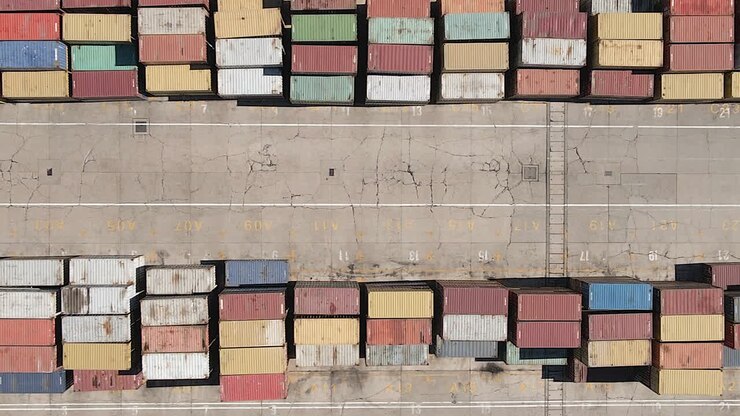 Vista aerea: Container di spedizione colorati impilati ordinatamente in un trafficato porto marittimo