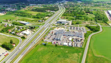 Buildings-of-logistics-center,-warehouses-near-the-highway,-view-from-height,-a-large-number-of-trucks-in-the-parking-lot-near-warehouse