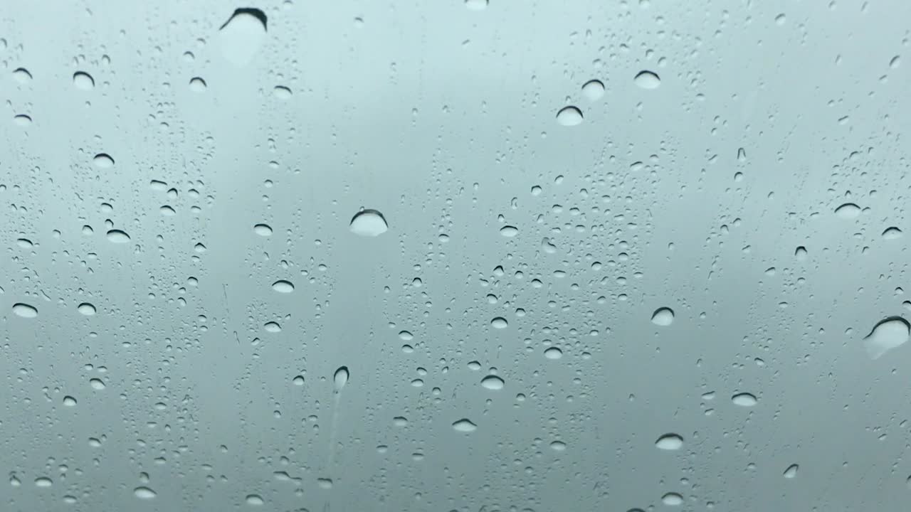 gotas de lluvia que fluyen sobre el parabrisas de un automóvil que conduce