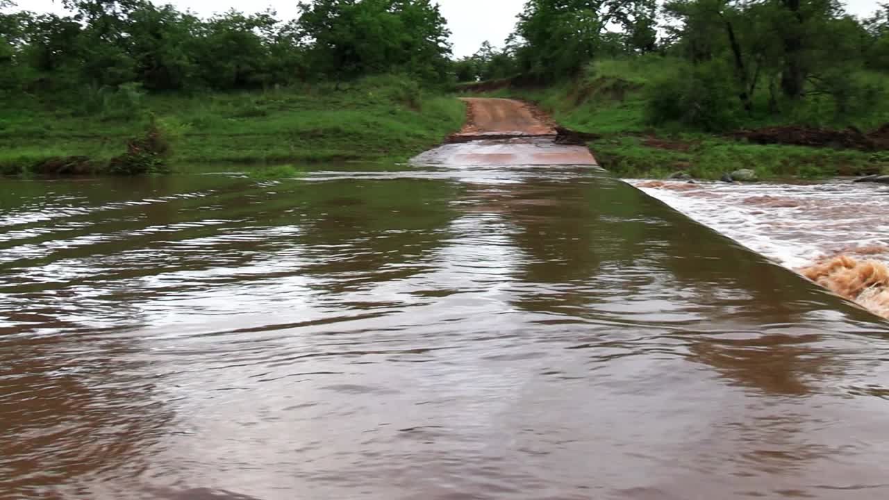 Remote countryside river crossing road submerged under water in Africa