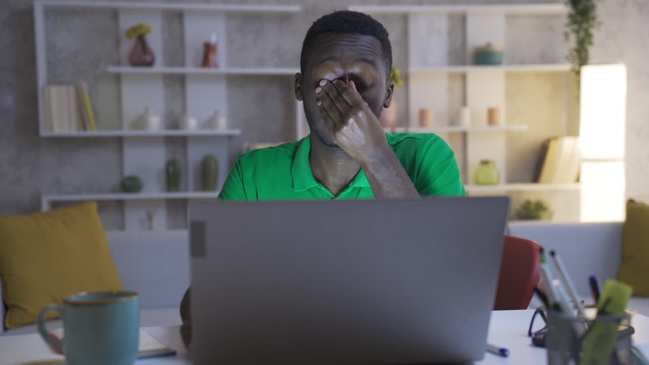 Besorgter und müder junger afrikanischer Mann arbeitet im Home-Office und fühlt sich überfordert.