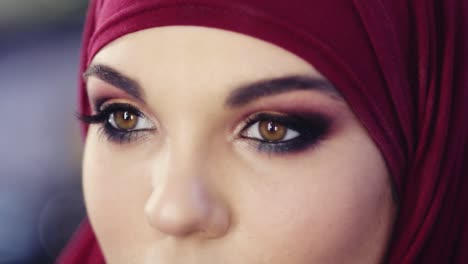 imágenes en cámara lenta de cerca de ojos humeantes maquillaje mirada. mujer irreconocible con hijab púrpura