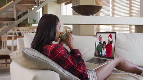 mixed race woman using laptop on video chat with family during christmas at home