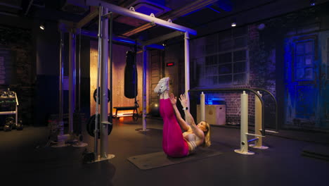 woman exercises lying on a gym mat, performing leg raises and pulses arms forward to enhance core strength, flexibility, and muscle control