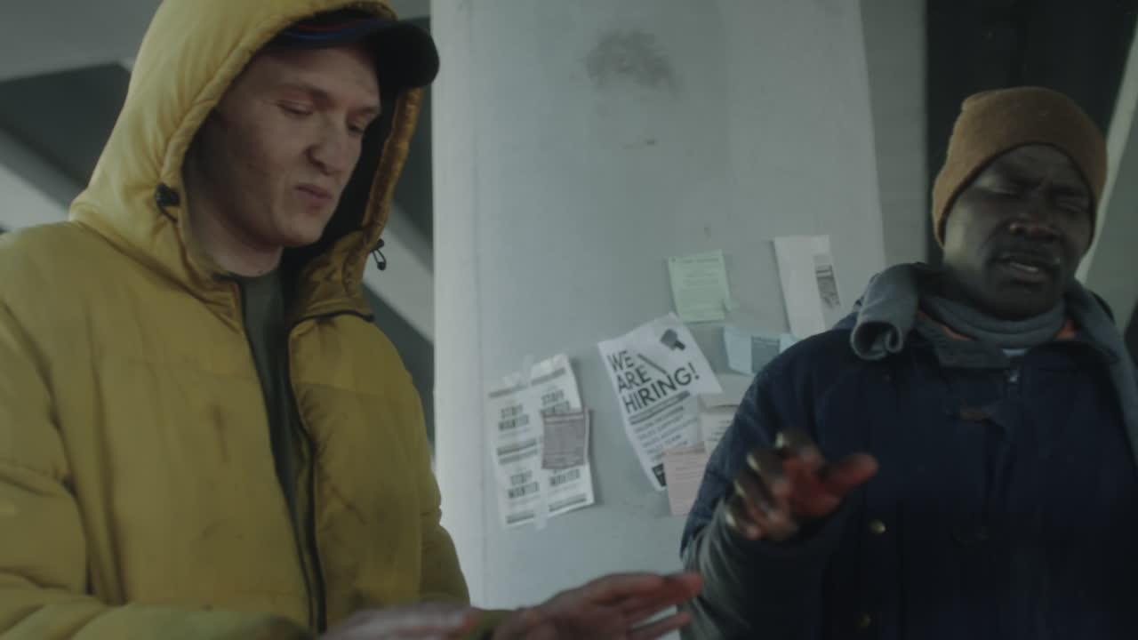 Men Huddling Under an Underpass with Job Posters in Winter