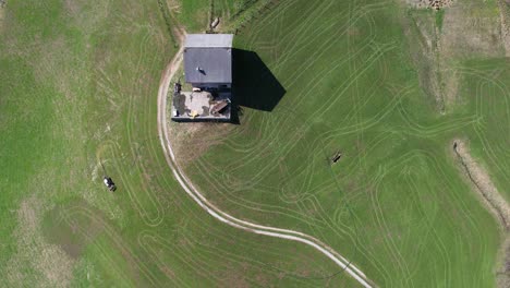 Vista-Aérea-De-Arriba-Hacia-Abajo,-Granjero-De-Montaña-Labra-Su-Campo-Con-Tractor-Y-Manguera