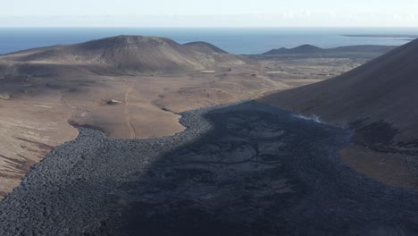 black basalt rock slow moving lava stream stretching towards ocean, iceland