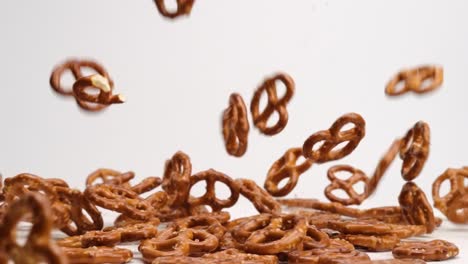 galletas saladas de pretzel torcidas que caen sobre una mesa blanca y rebotan en un montón a cámara lenta