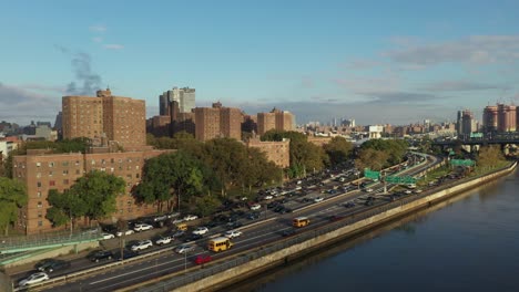 aerial-shot-follows-cars-uptown-on-the-Harlem-River-Drive-in-New-York-City,-schoolbuses-in-interest