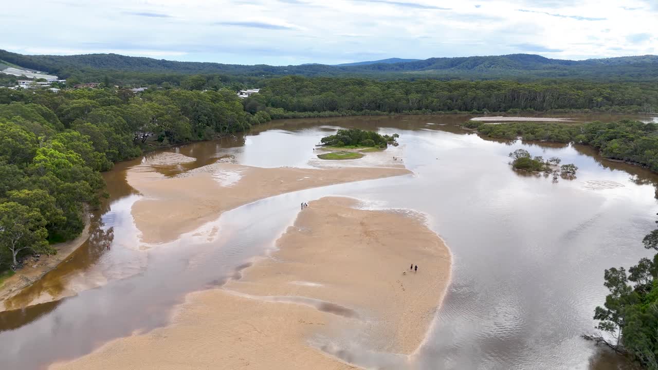 Drone glides over winding river, mangrove trees, and sandbanks under soft daylight, wide perspective