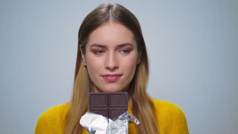 portrait of smiling woman looking with chocolate bar at camera indoors