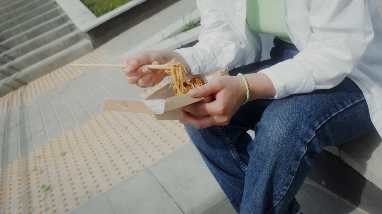 mujer comiendo fideos al aire libre
