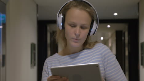 mujer con auriculares cantando y bailando con tableta