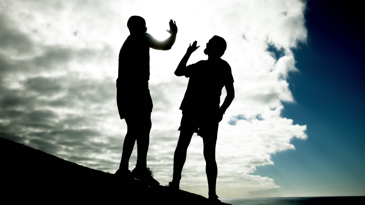 Silhouettes of people running on a hill against a cloudy sky