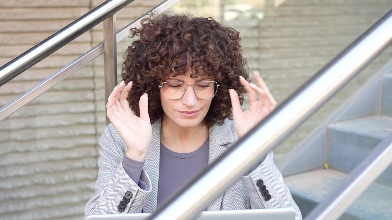 Un giovane professionista riflessivo e innovativo lavora diligentemente su un laptop all'aperto.