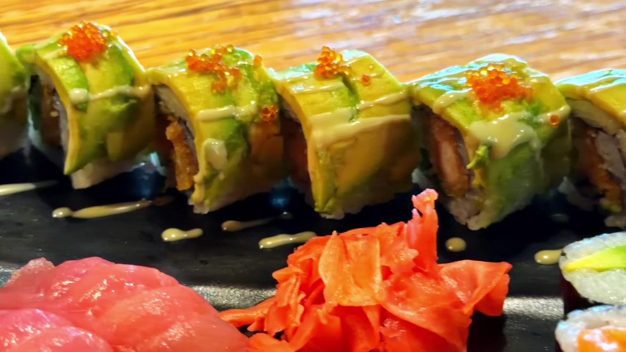 Carrellata a sinistra di un piatto di sushi fresco con Dragon Roll e Maki, che evoca l'arte culinaria giapponese