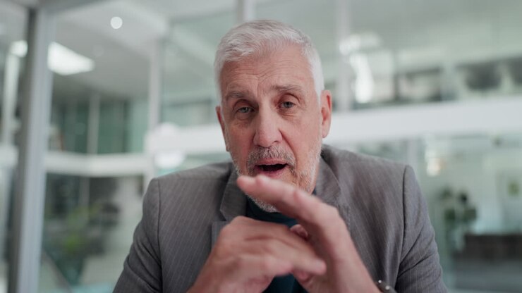 Senior Businessman Talking and Gesturing During Video Call