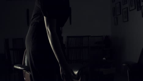 waman entre dans une pièce sombre et prend un livre de photographie sur une table basse