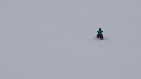 snowmobile traveling on fresh snow, aerial tracking shot 4k