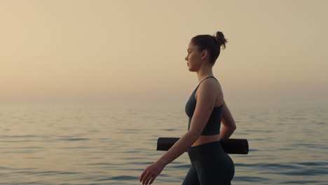 confident sportswoman walking beach at sunset close up. girl going near ocean.