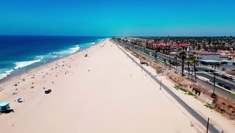 Flying-over-Huntington-Beach-with-a-police-car-in-view-and-almost-no-people-on-the-sand