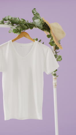 vertical video of close up of white t shirt hanging and straw hat with copy space