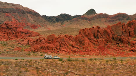 aerial view of a truck with trailer driving on a road in middle of red rocks in nevada, usa