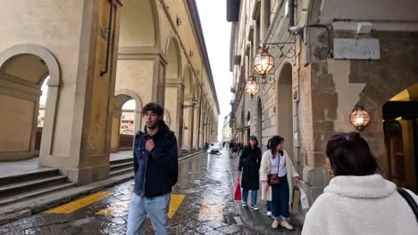 people walking under arches in florence, italy