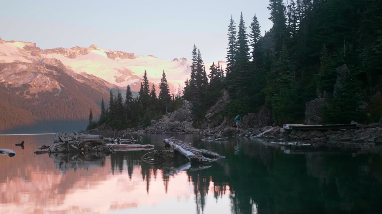 Persona che corre lungo un lago nella natura selvaggia della Columbia Britannica, al rallentatore.