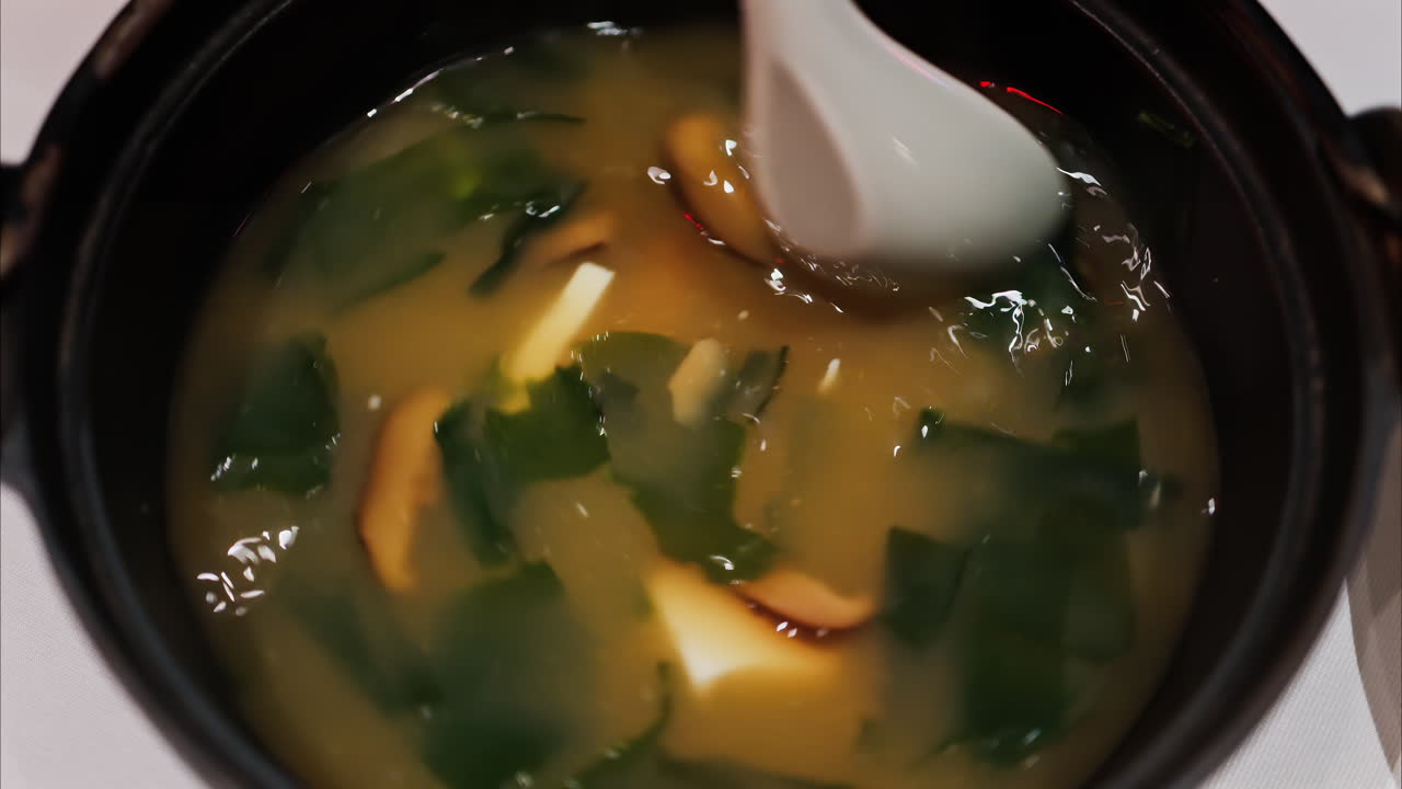 Close up of a woman mixing a miso soup at a restaurant