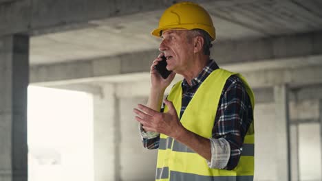 caucasian senior engineer talking on the phone on construction site.