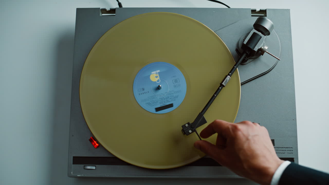 Man start vinyl play putting yellow disc on classic gramophone at home closeup
