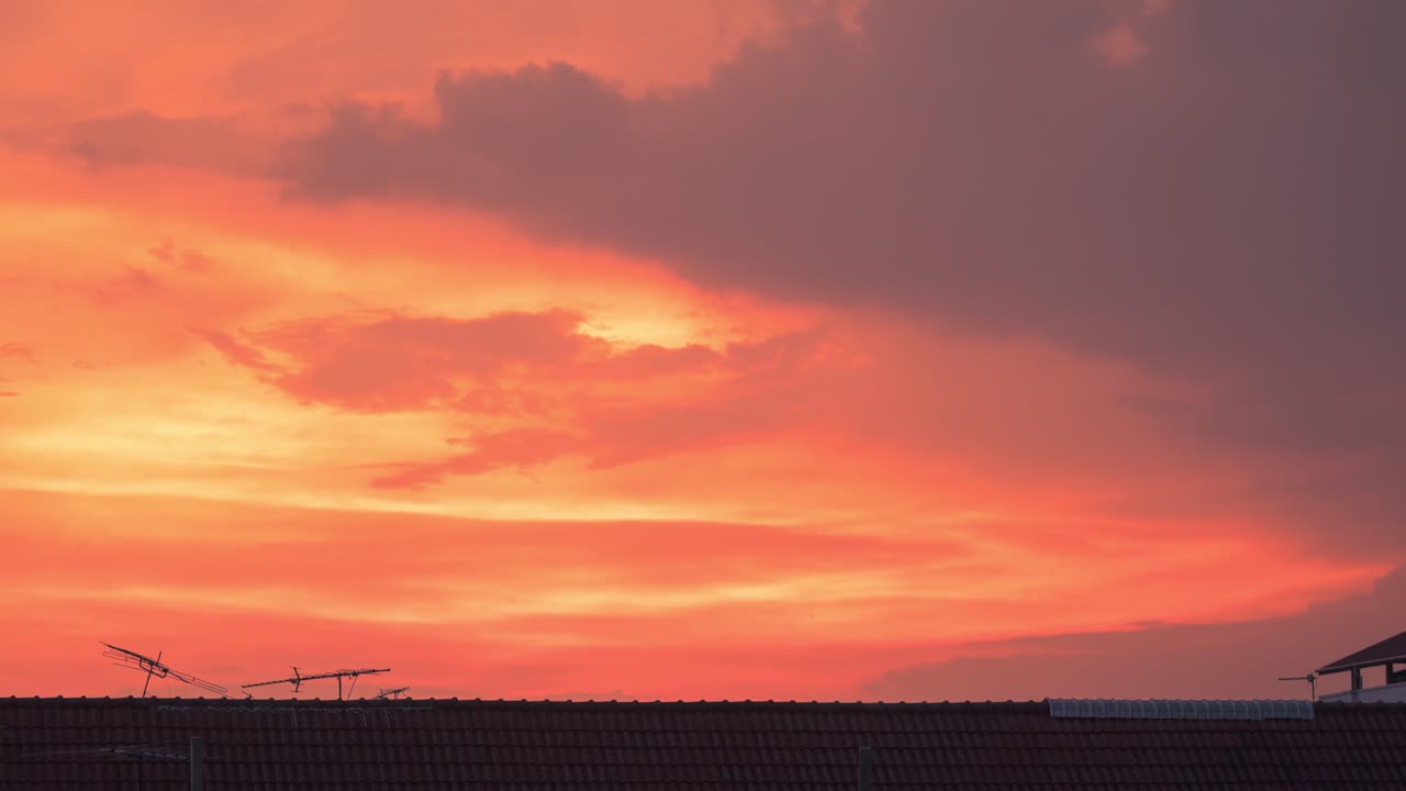 Timelapse of the colorful sunset above the house roof with antennas