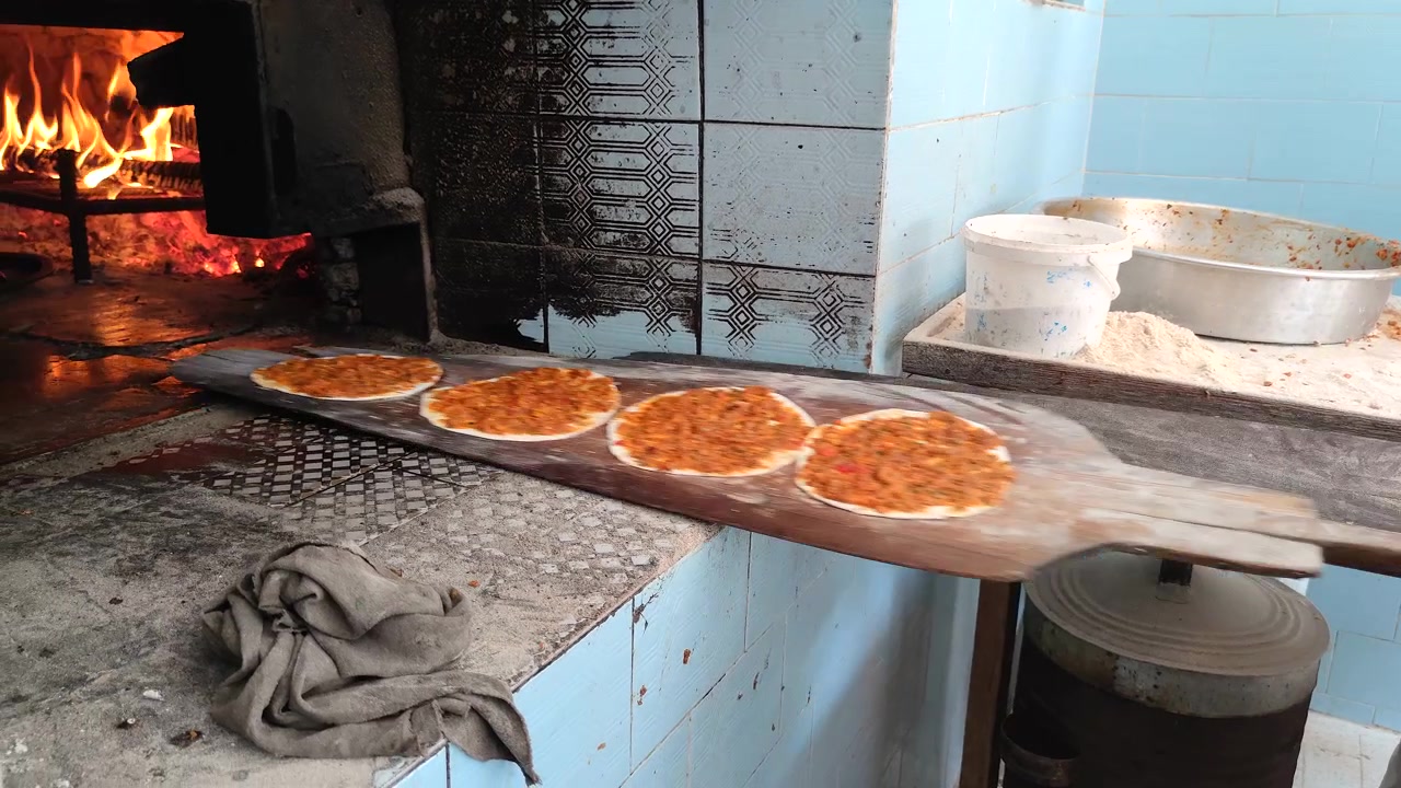 Leipuri valmistamassa ja paistamassa perinteistä lahmacunia puu-uunissa