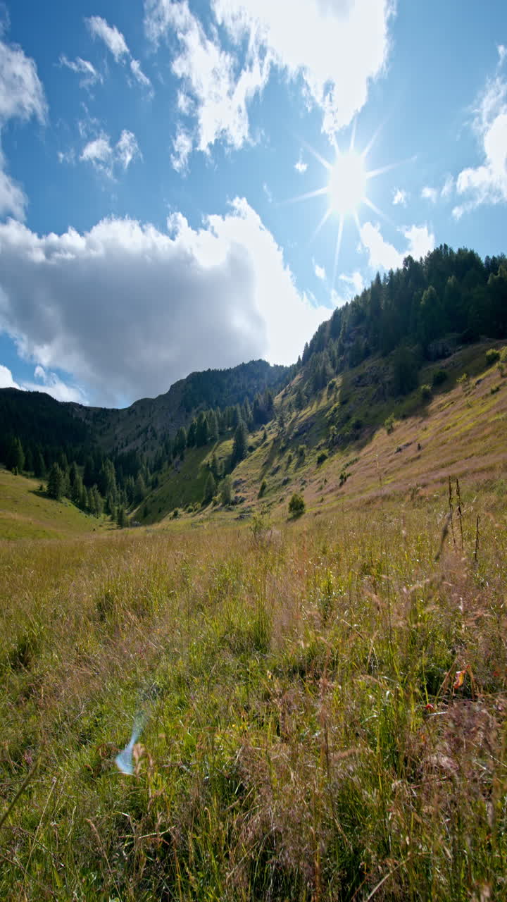 Sole splendente su montagne erbose in uno scatto paesaggistico verticale sereno