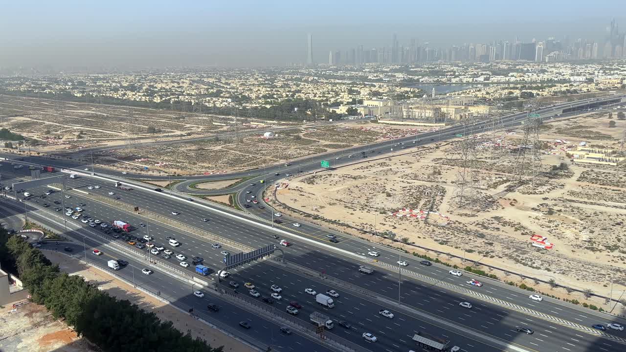 Veicoli che si muovono lungo Al Khail Road a Dubai, mentre lo skyline della città si erge sullo sfondo, illustrando la vita quotidiana negli Emirati Arabi Uniti.