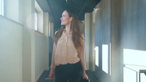 Happy-woman-with-travel-suitcase-walking-at-hotel-corridor