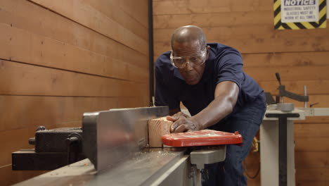 male carpenter using plane in woodworking woodshop