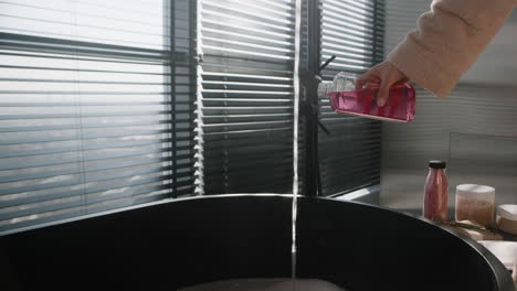 Pouring Bubble Bath into a Modern Black Tub