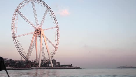 rueda grande de lapso de tiempo en el océano, puerto deportivo de dubai, puerto, salida del sol, tiro estático, ángulo bajo