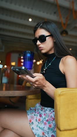 woman using phone and drinking in a cafe