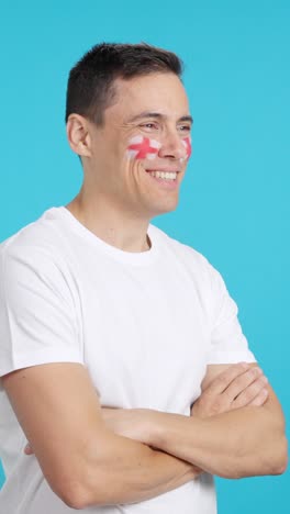 Happy man with english flag painted on face looking away
