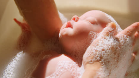 Mother-giving-her-baby-boy-a-bath-in-bathroom-4k