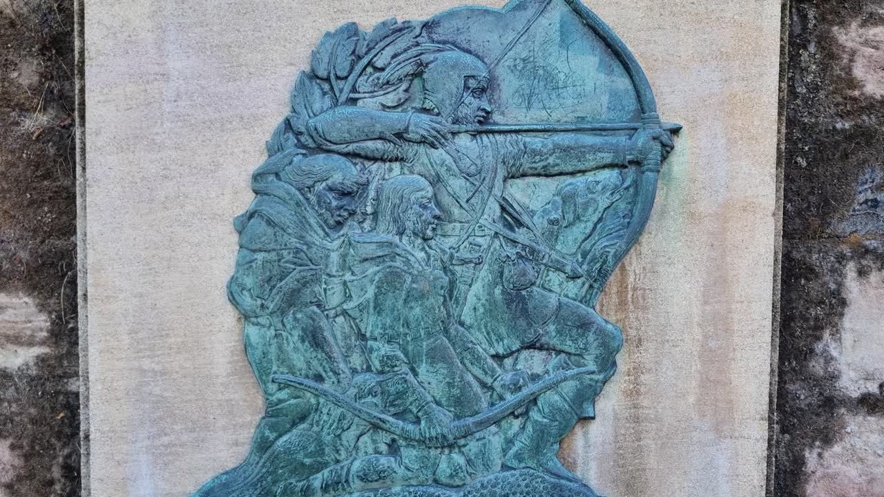 Decorative plaque on a Nottingham castle wall portraying Robin Hood with bow drawn, commemorating the city’s legendary outlaw and folk hero