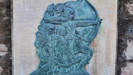 decorative plaque on a nottingham castle wall portraying robin hood with bow drawn, commemorating the city’s legendary outlaw and folk hero