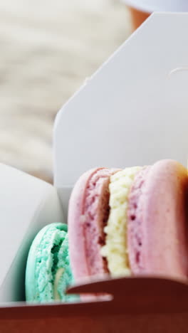galletas de macarrón coloridas en una bolsa de papel con café