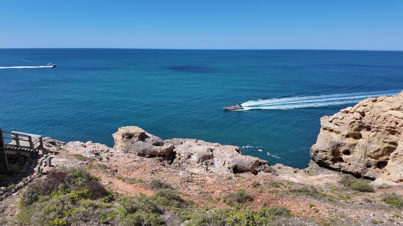 Breathtaking view of the rocky coastline and turquoise waters of the Atlantic Ocean, featuring motorboats navigating near the cliffs