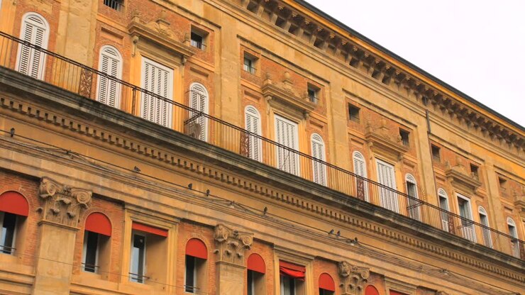 Toma en contrapicado de las antiguas ventanas con maineles del Palazzo Accursio, ayuntamiento en el centro de Bolonia, Italia, en un día nublado