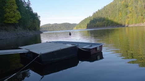 steady shot of a wooden landing stage with a anchored boat at the local lake on a sunny day