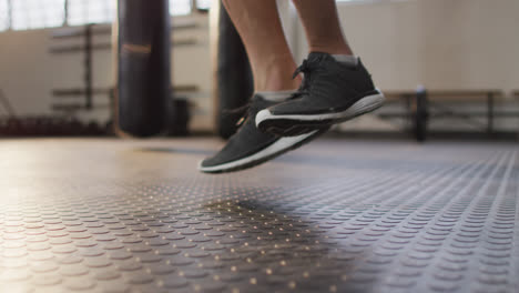 Sección-Baja-De-Un-Hombre-Caucásico-En-Forma-Trabajando-Con-Cuerdas-Para-Saltar-En-El-Gimnasio